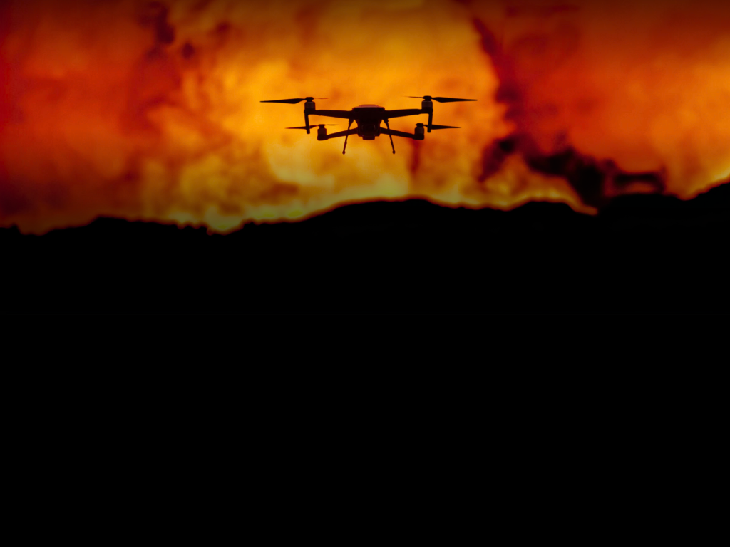 Drone silhouette against an orange fire scene in an IRIS Network promotional composite